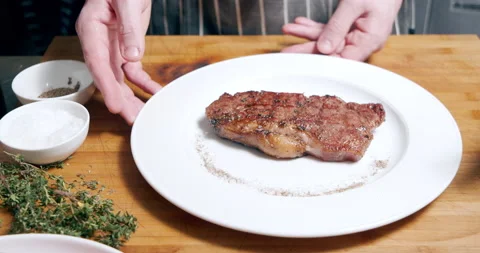 Close-up of a grilled marbled beef steak with spices and herbs on a white plate Stock Footage 149254662