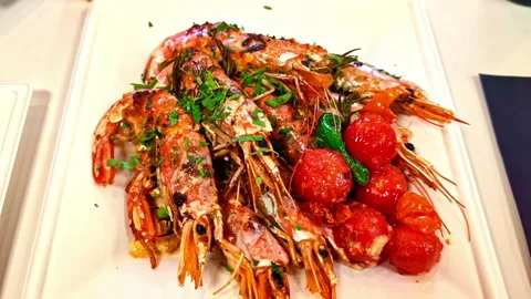 Close-up of grilled prawns with herbs and roasted cherry tomatoes on a white Stock Footage 333318914