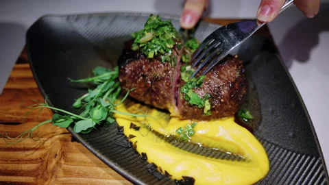 Close up of a grilled steak being sliced with a knife and fork at a restaurant Stock Footage 335470103