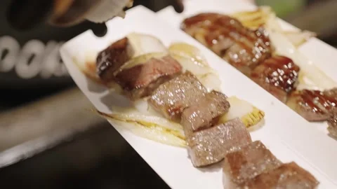 Close-up of Grilled Wagyu Beef Steak Cubes on White Plate Stock Footage 337441096