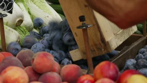 Close-up of grocery worker is pours plums from wooden box on store shelves. Stock Footage 140984894