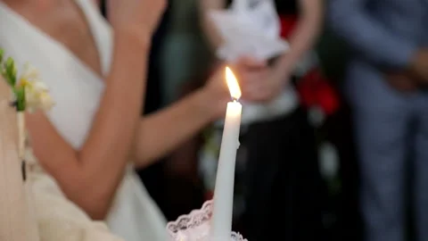A close-up of the groom and bride hands holding candles in a church, making the Stock Footage 324815516