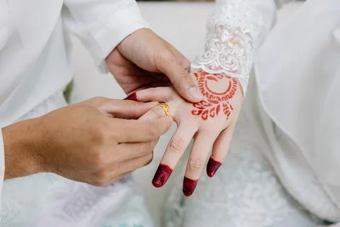 Close-up of a groom's hands sliding a gold ring onto the bride's finger Stock Photos