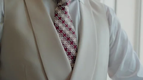 Close-up of a groom's patterned tie against a cream colored vest Stock Footage 282251764