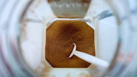 Close-up of ground coffee in a white container with spoon, shallow depth of.. Foto stock