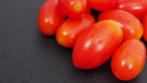 Close up group of Cherry Tomatoes on black background. Stock Photos