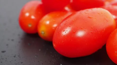 Close up group of Cherry Tomatoes on black background. Stock Photos