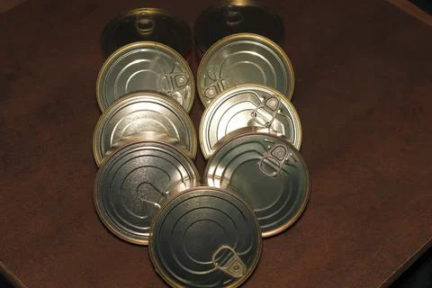 Close-up of a group of closed tin cans with a key to open them. Stock Photos