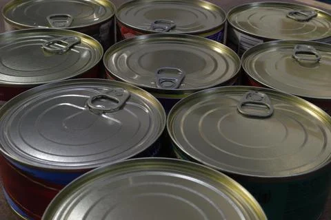 Close-up of a group of closed tin cans with a key to open them. Stock Photos