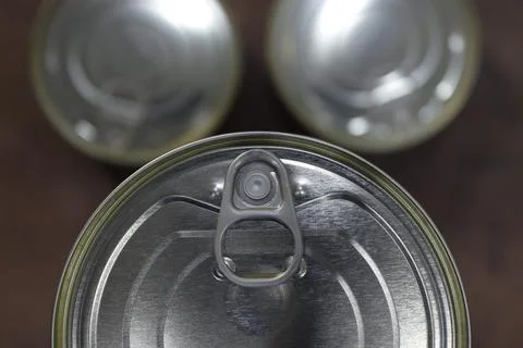 Close-up of a group of closed tin cans with a key to open them. Stock Photos