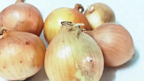 Close-up of a group of fresh raw yellow onions isolated on white background. 스톡 동영상 338991260