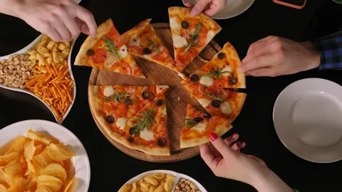 Close-up of a group of friends simultaneously taking slices of pizza in a cafe. Stock Footage 145868737
