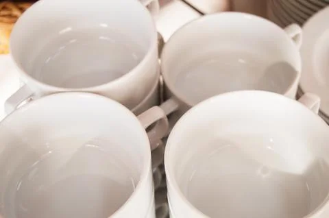 Close-up of a group of white ceramic tea cups and plates standing on a table  Stock Photos