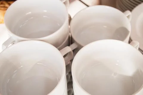 Close-up of a group of white ceramic tea cups and plates standing on a table  Stock Photos