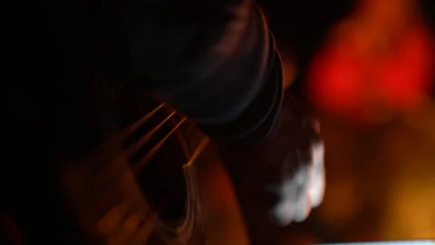 Close-up of guitar and hand of performer playing by the fire at night Stock Footage 140451899