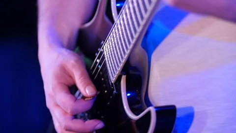 Close up of a guitar and the hand with pick moves along stings Vidéo 103389204