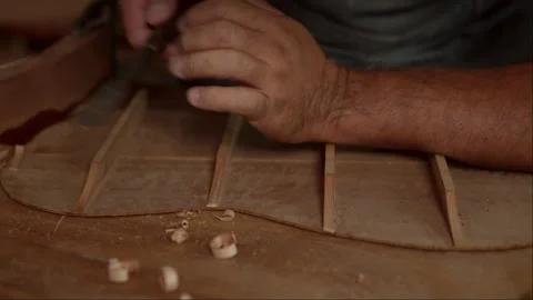 Close-up of guitar luthier using chisel to shave bracing of acoustic guitar. Stock Footage 251803493