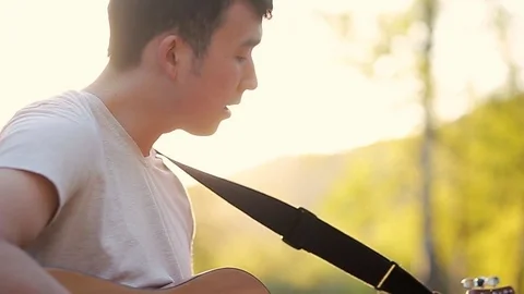 Close up of a guitar player singing and playing the guitar in the beautiful 動画素材 76009987