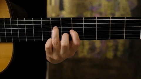 Close-up of a guitarist's fingers pressing strings on an acoustic guitar Stock Footage 335372476
