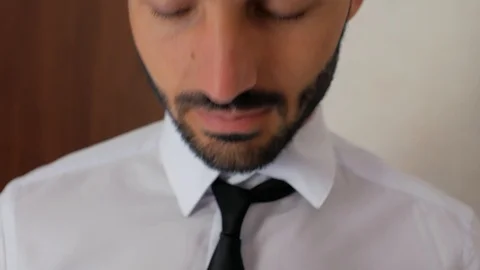 Close up of a guy with a beard in a white shirt is tying a tie and straightens Stock Footage 111725157