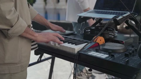 Close-up of a guy in a beige shirt playing an electronic synthesizer in front of Stock Footage 195556762