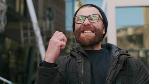 Close up of guy in glasses looking at phone screen and rejoicing while walking Stock Footage 141535626
