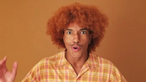 Close up, guy looking at the camera with big eyes, says wow, isolated on brown Video stock 253932097