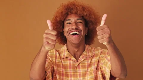 Close up, guy showing double thumbs up gesture isolated on brown background in Stock Footage 253931916