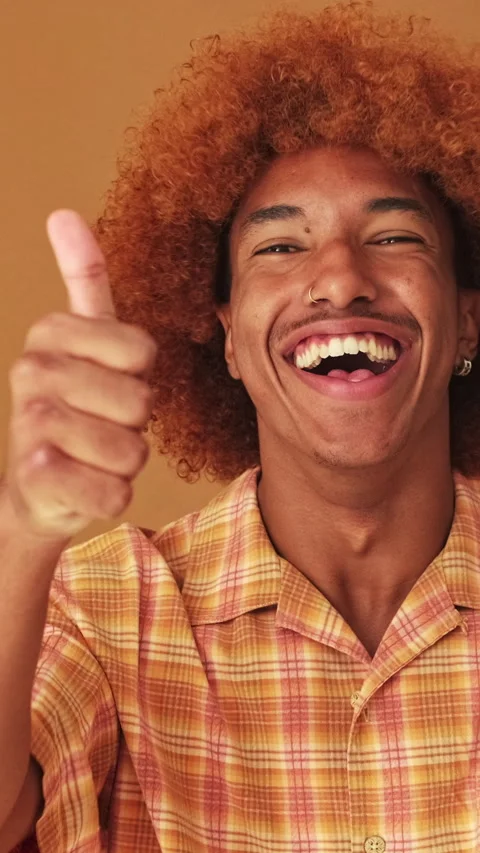 Close up, guy showing double thumbs up gesture isolated on brown background in Stock Footage 255963888