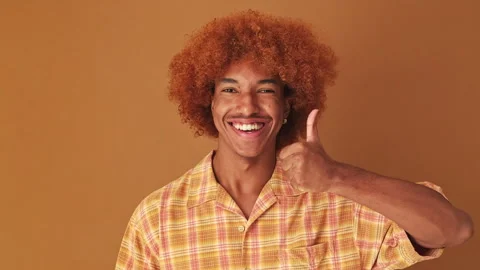 Close up, guy showing thumbs up gesture isolated on brown background in studio 스톡 동영상 255963867