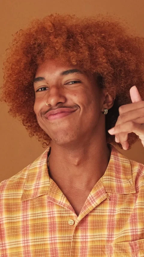 Close up, guy shows call me phone hand sign gesture, isolated on brown Stock Footage 262325826