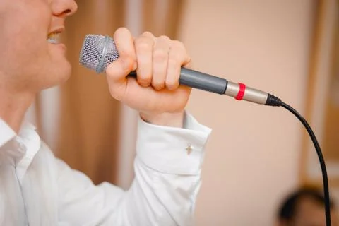 Close-up Guy singing into the microphone close-up. Profile of emotionally sin Stock Photos