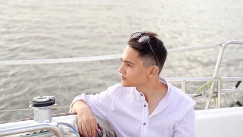Close-up of a guy sitting aft of a moving white yacht. Hearing impaired young Stock Footage 164387279