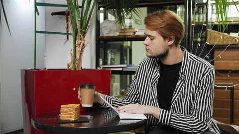 Close-up of a guy sitting in a caf writing in a notebook. Cafe Stock Footage 169452853