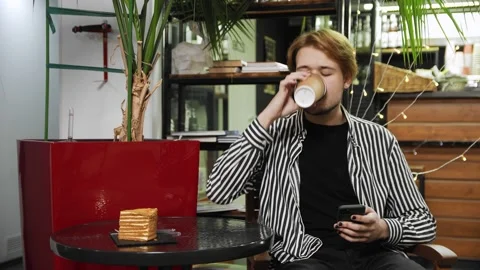 Close-up of a guy sitting in a cafe and typing a message on his phone. Coffee Stock Footage 169451717