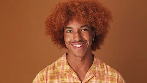 Close up, guy smiling widely looking at the camera isolated on brown background Stock Footage 253931965