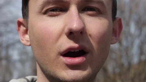 Close-up of a guy smokes an electronic cigarette and looks into the camera Video stock 73956035