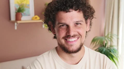 Close-up of guy standing in cozy living room looking at the camera with smile Stock Footage 252030955