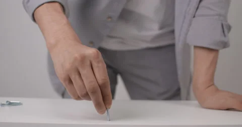 Close-up of a guy's hand twisting the screw. The process of assembling a wooden Stock Footage 167113943