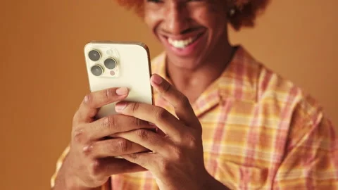 Close-up, guy's hands holding mobile phone, isolated on brown background Vídeo Stock 253933214
