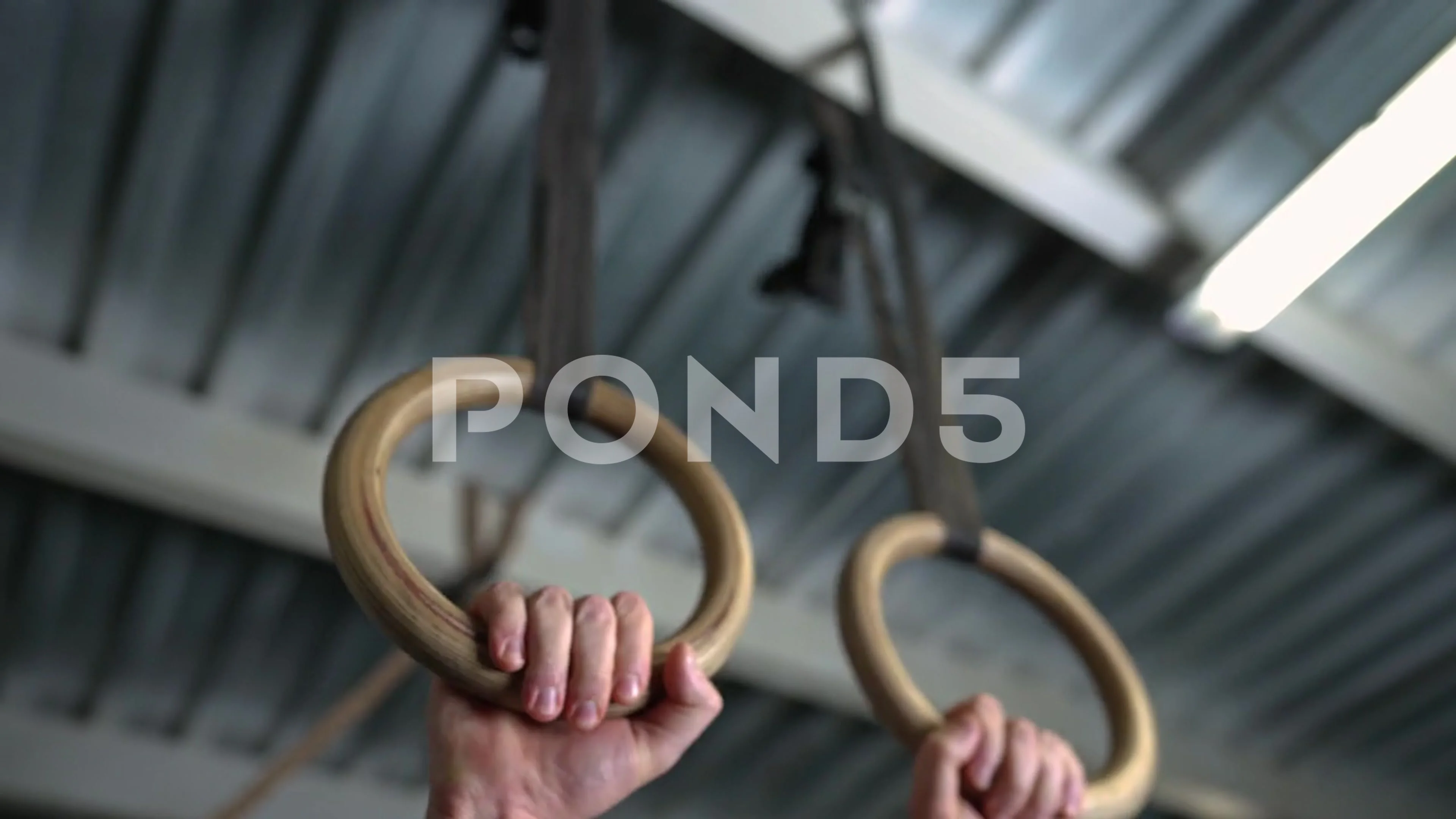 Cheerful athlete hanging with gymnastic rings against wall at gym stock  photo