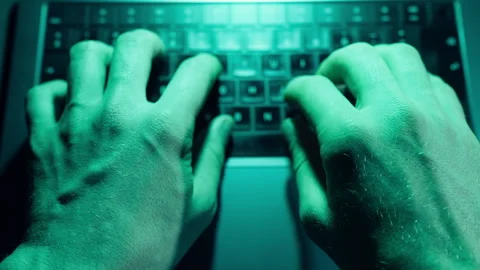 Close-up of hacker hands typing rapidly on laptop keyboard with green neon light Stock Footage 346105525