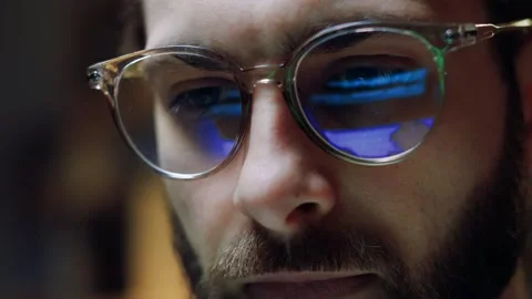 Close-up hacker's eyes in glasses hacking website at night time. Close up male 動画素材 263546342