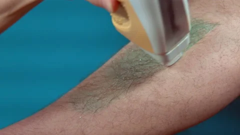 Close up of hairy leg of a man using wax epilation at home on a turquoise Stock Footage 144453830