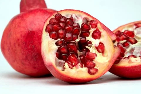 Close up of half-divided pomegranates in white background Stock Photos