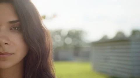 Close up of half face of beautiful young curly-haired brunette woman outdoors Stock Footage 244379874