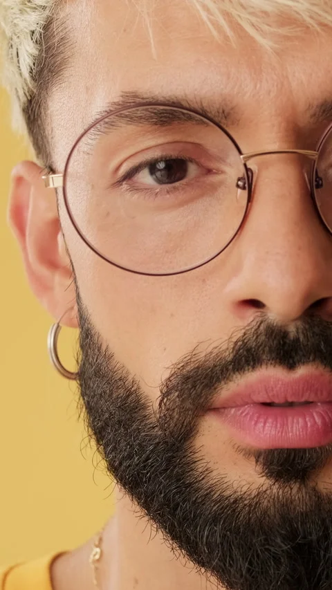 Close up, half face man smiling looking at camera isolated on yellow background Stock Footage 261468019