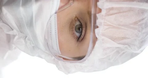 Close-up of half of famale doctor's face. She is in a protective suit, mask and Stock Footage 164241548