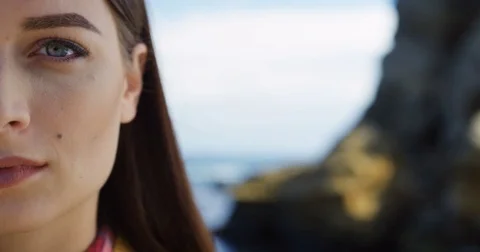 Close up of half femane smiling face on the blurred rochy sea background Stock Footage 82978253