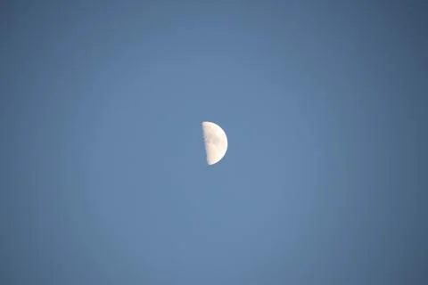Close up of a half moon during say time with a blue sky. Stock Photos